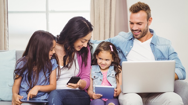 family sitting using multiple smart devices in the home